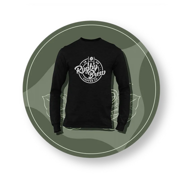 A black long-sleeve rugby t-shirt with a white circular graphic on the chest reading 'Rugby Brew COFFEE CO', presented on a dark olive green circular background with a white border.